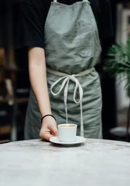A person delivering a cup of coffee