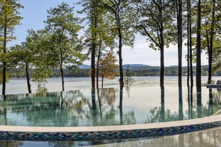 Infinity pool overlooking lake and mountain scenery