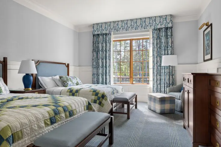 Double queen guest room with blue curtains and chairs