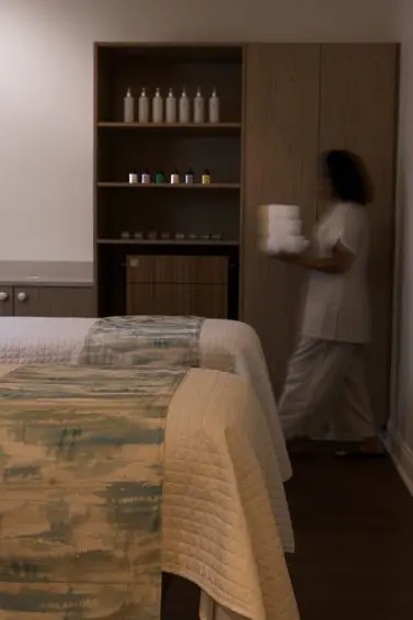 Spa staff carrying towels through tranquil treatment room.